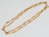 a close up of a gold necklace with pearls on a white background