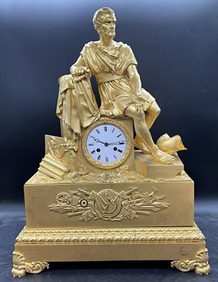 une statue en or représentant un homme assis sur une table, avec une horloge