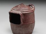 une image représentant un pot marron avec un couvercle, posé sur une surface blanche