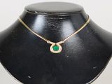 une photo d'un collier orné d'une pierre verte, porté par un mannequin