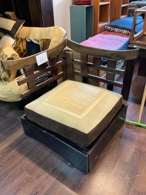 un fauteuil et un pouf dans une pièce où se trouvent une table et des chaises