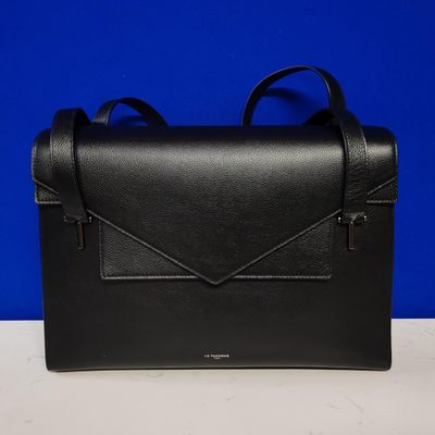 a black leather bag with an envelope on top of it