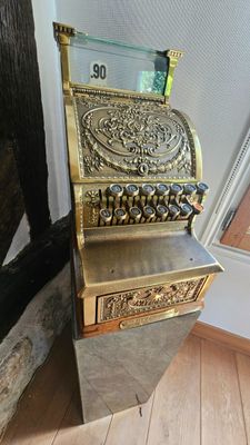 une caisse enregistreuse à l'ancienne posée sur un plancher en bois