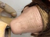 a hand that is holding a doll head and a pair of scissors