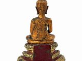 statue of a buddha sitting on a pedestal with a red and gold base