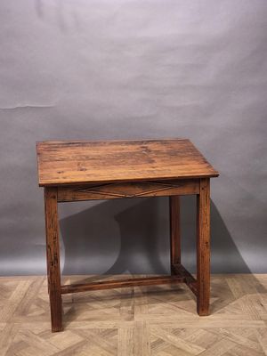 an old wooden table on a parquet floor against a grey wall