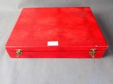 an old red suitcase sitting on top of a gray surface