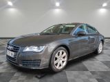 the grey audi is parked on a checkered floor in a garage
