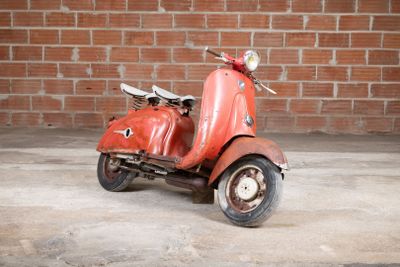 a red scooter that is parked in front of a brick wall