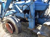 a blue tractor that is sitting in the grass