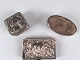 trois petits objets argentés posés sur une surface blanche