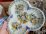 a person holding a plate in their hand in front of a pile of dishes