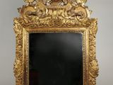 un miroir au cadre doré ouvragé, avec un verre noir au centre