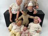 five baby dolls sitting next to each other on a black box