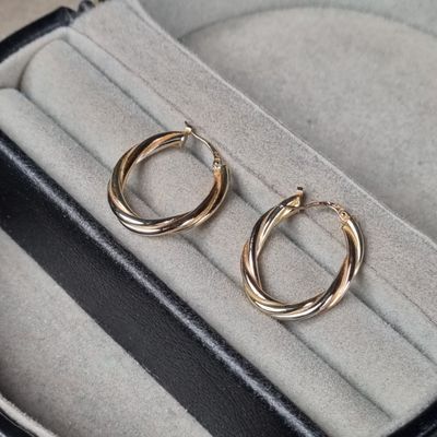 deux paires de boucles d'oreilles créoles en or posées sur un étui noir