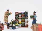 many figurines of people standing in front of a flower stand