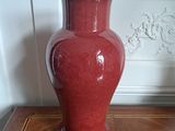 a red vase sitting on top of a wooden table