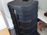 une valise noire posée par terre à côté d'une étagère