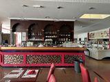 des tables et des chaises dans un restaurant, avec un bar en arrière-plan
