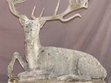 statue d'un cerf assis sur une plate-forme en bois sur laquelle sont posés ses bois