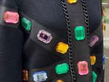 a mannequin wearing a black sweater with multi colored jewels on it