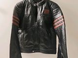 black leather jacket hanging on a hanger on a white wall