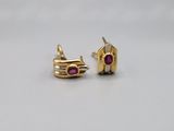 a pair of gold and ruby earrings on a white surface