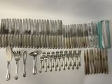 a lot of silverware on a table with a knife, fork, spoon, and spoon rest