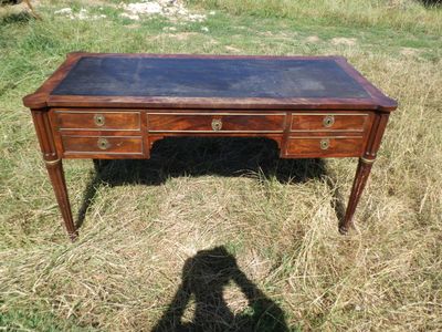 un bureau en bois avec un plateau en verre, posé dans l'herbe