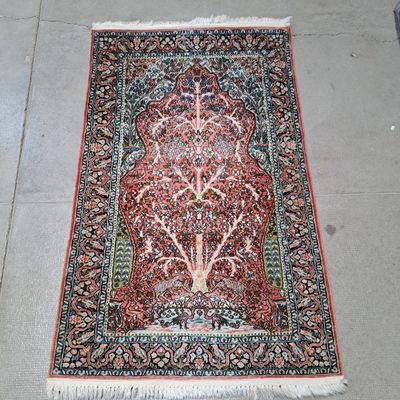 un tapis oriental posé au sol, orné d'un motif représentant l'arbre de vie