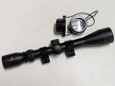 a close up of a rifle scope and a compass on a table