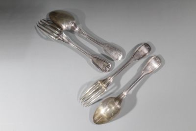 trois cuillères et deux cuillères en argent sur une surface blanche