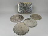 four silver coasters and a silver purse on a white surface