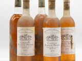 quatre bouteilles de vin posées les unes à côté des autres sur une surface blanche