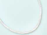 a close up of a silver necklace on a blue surface