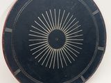 une assiette noire ornée d'un motif en rayons de soleil