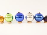 six different colored glass ornaments are lined up in a row