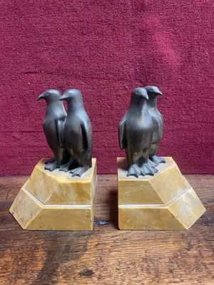 une paire d'oiseaux en bronze posés sur des socles en marbre, posés sur une table en bois