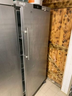 un réfrigérateur en acier inoxydable dans une cuisine dont l'un des murs est en bois