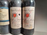 three bottles of red wine are lined up on a table