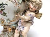 a statue of a cupid holding a flower in front of a vase