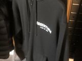 un sweat à capuche noir accroché à un portant dans un magasin de vêtements