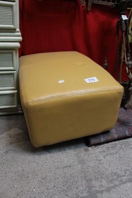 un pouf jaune posé devant un mur rouge
