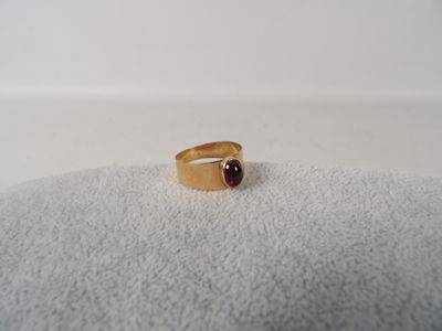 Gros plan sur une bague en or ornée d'une pierre rouge