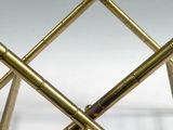a close up view of a gold bamboo stool with four legs