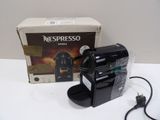 une machine Nespresso posée sur une table à côté d'une boîte de café Nespresso