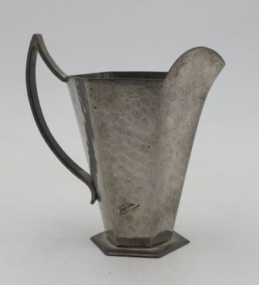 an antique silverware pitcher with a curved handle on a stand