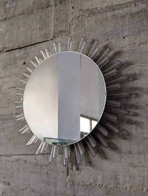 un miroir accroché au mur, orné d'un motif en rayons de soleil