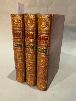 trois livres sont empilés sur une surface blanche