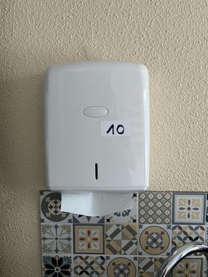 un distributeur de papier essuie-tout fixé au mur au-dessus d'un lavabo